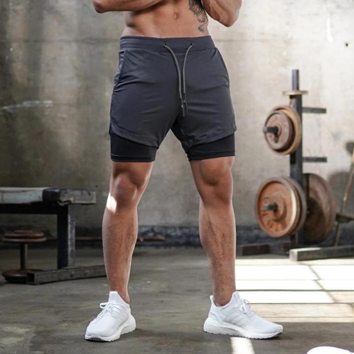 Person wearing dark gray athletic shorts in a gym setting