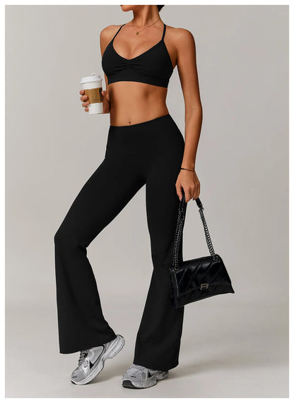 Person wearing a black sports bra and leggings holding a coffee cup and black handbag.