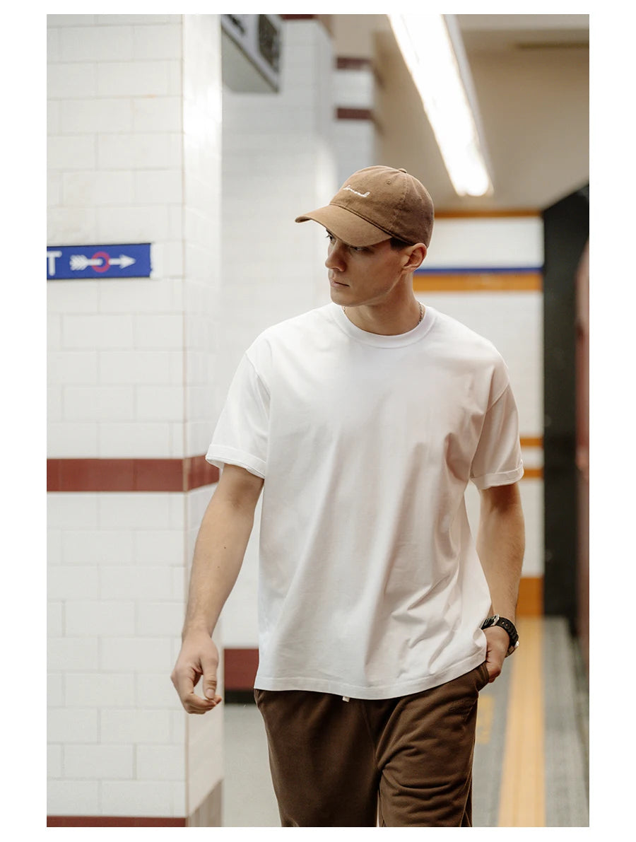 Person wearing a white t-shirt and brown cap in an indoor setting
