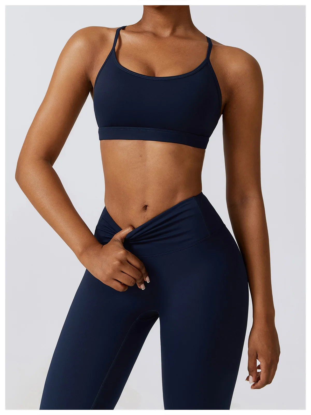 Person wearing a navy sports bra and leggings on a light gray background