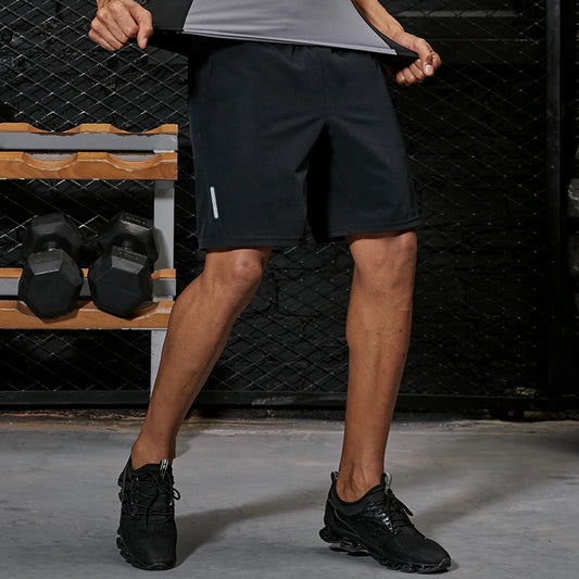 Person wearing black athletic shorts in a gym setting with weights and a bench in the background.