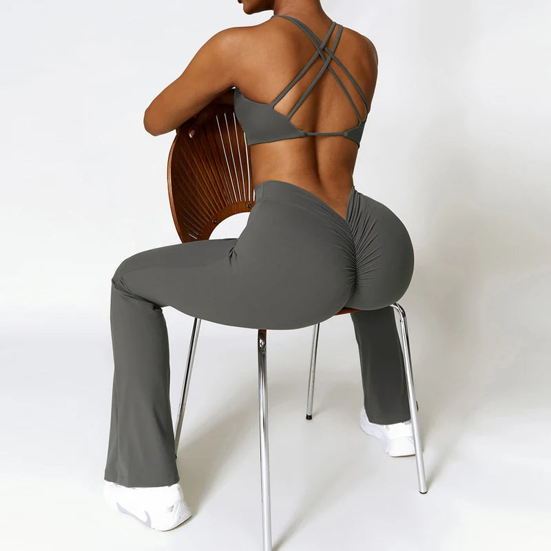 Person wearing a gray sports bra and leggings sitting on a chair with a white background