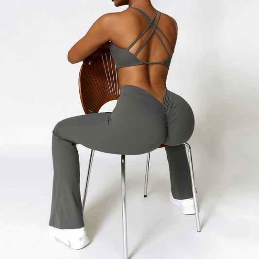 Person wearing a gray sports bra and leggings sitting on a chair with a white background