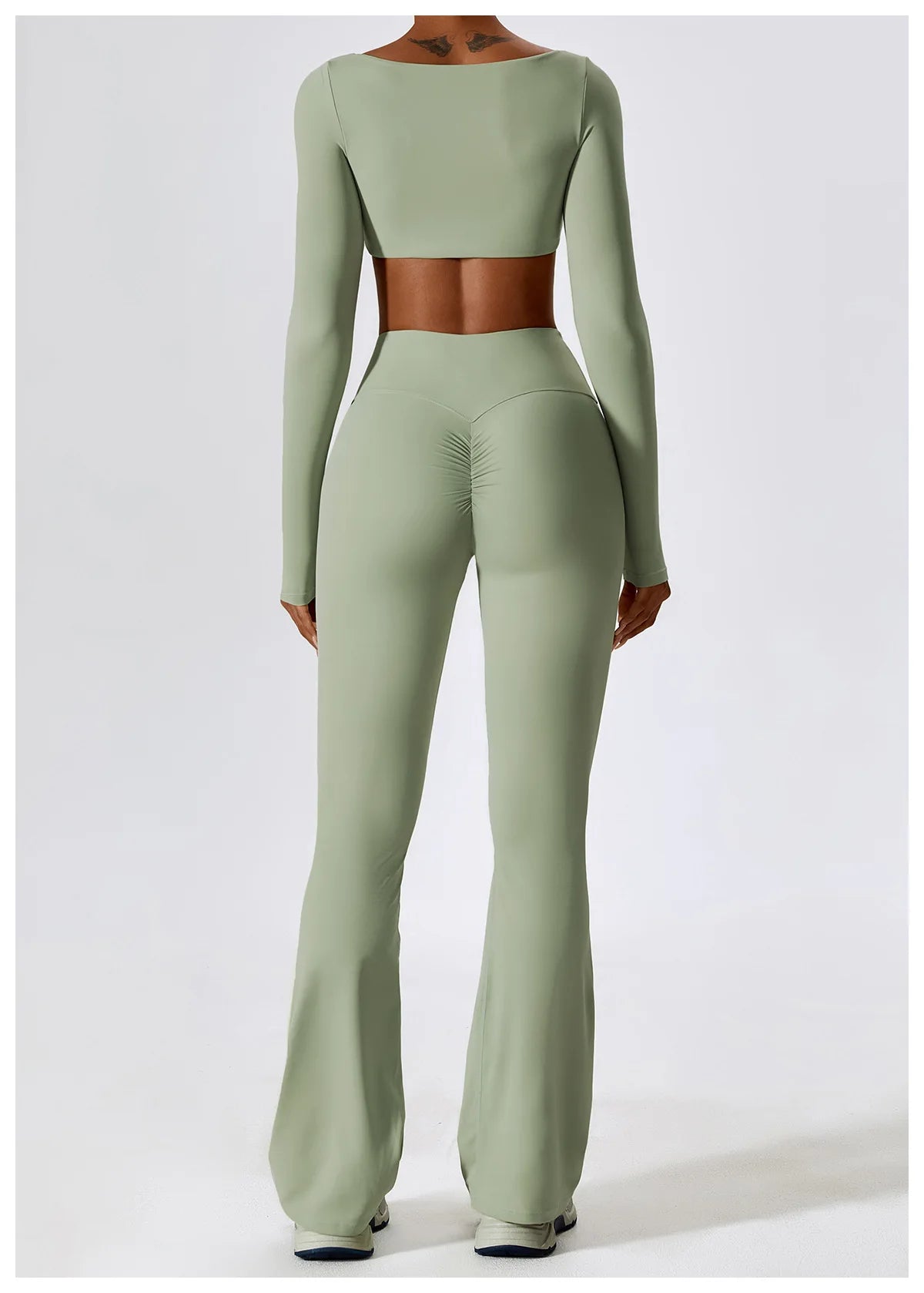 Person wearing a green long-sleeve top and flared pants on a white background