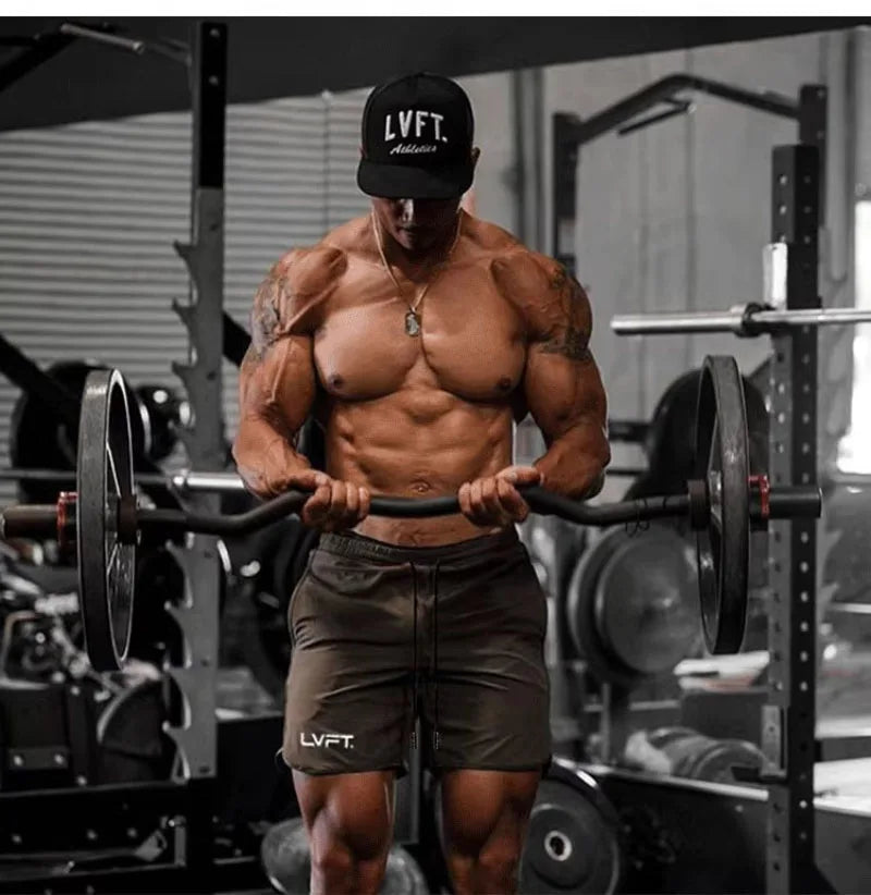 Muscular man lifting weights in a gym wearing an LVFT cap and shorts.