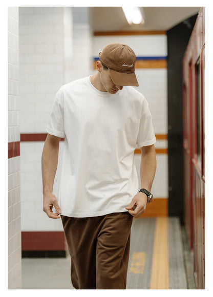 Person wearing a white t-shirt and brown pants in a tiled hallway