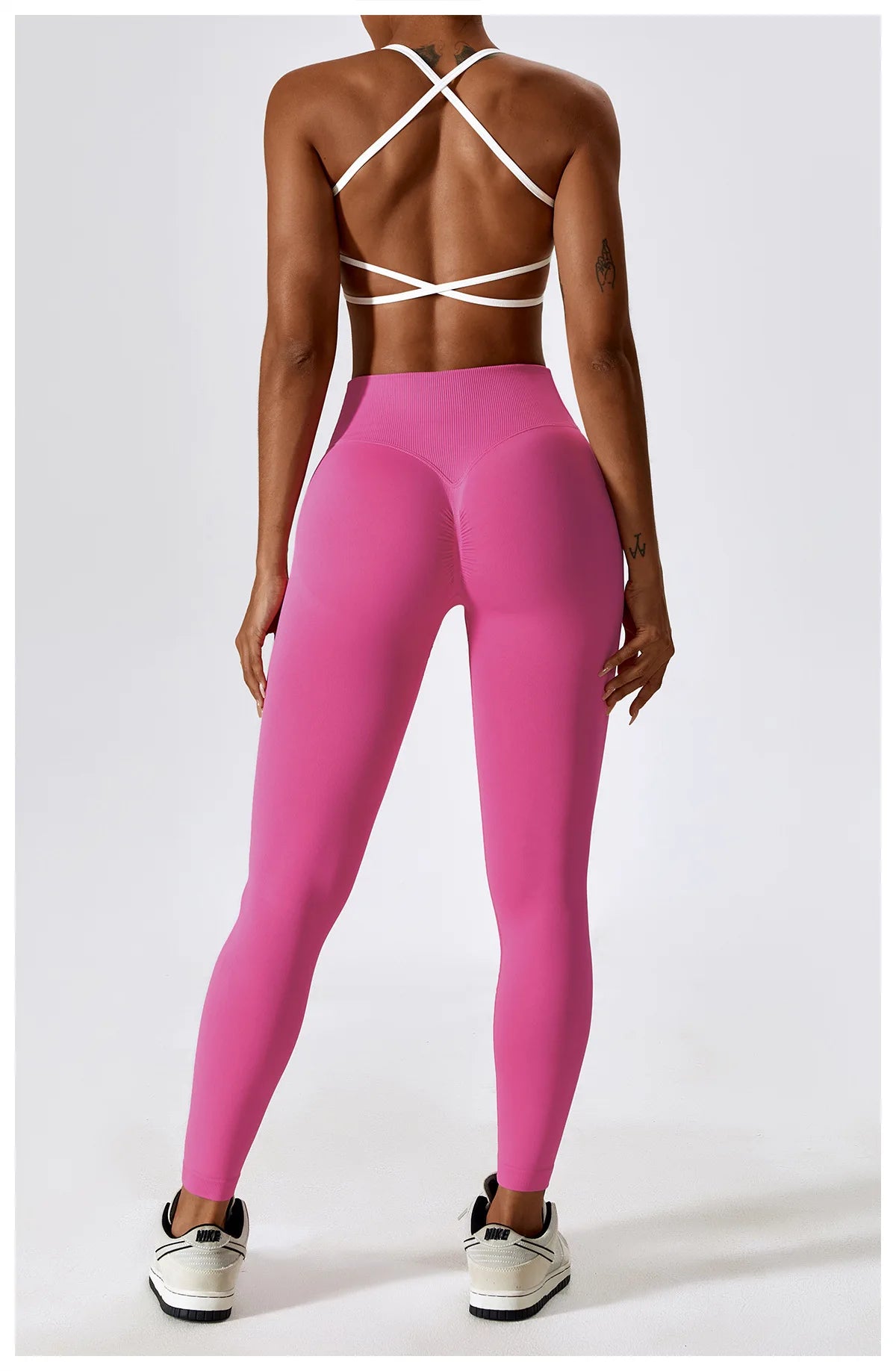 Person wearing pink leggings and a strappy top on a white background