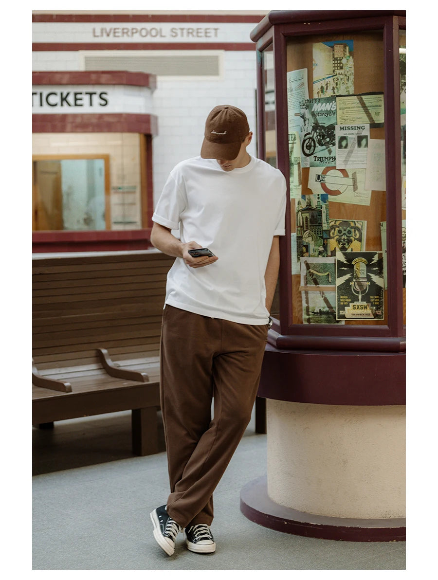 Person standing in front of a vintage telephone booth with posters on the side, at Liverpool Street station.