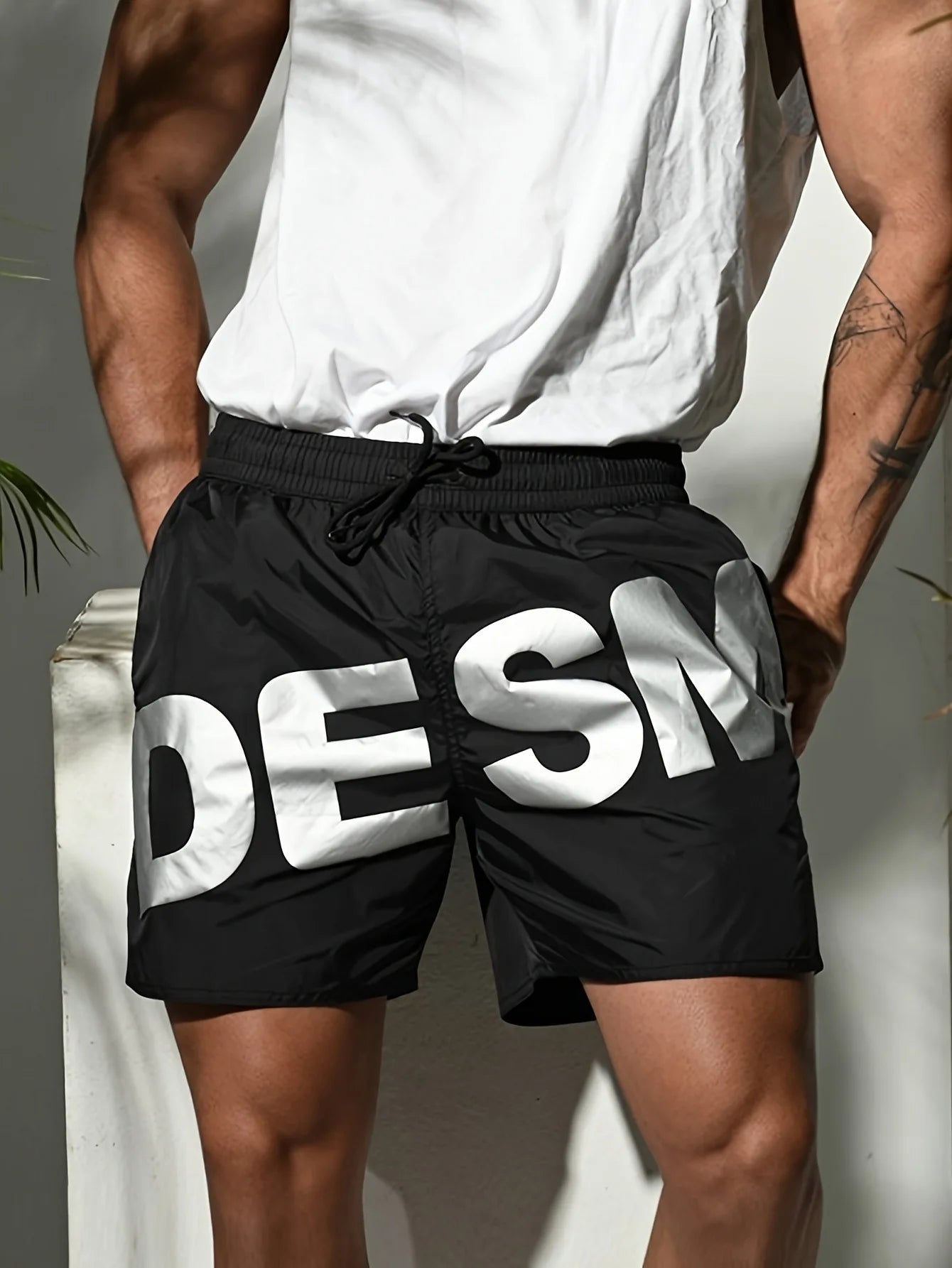 Person wearing black shorts with 'DESM' branding against a neutral background
