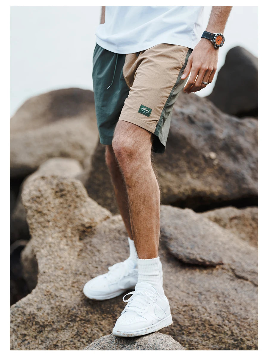 Person wearing green and beige shorts with white sneakers on a rocky surface