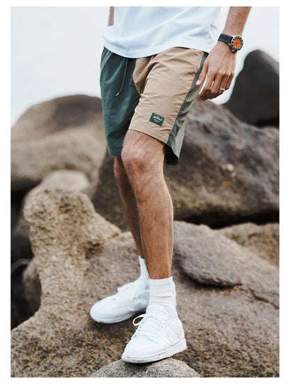 Person wearing green and beige shorts with white sneakers on a rocky surface