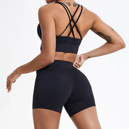 Person wearing a black sports bra and high-waisted shorts on a white background